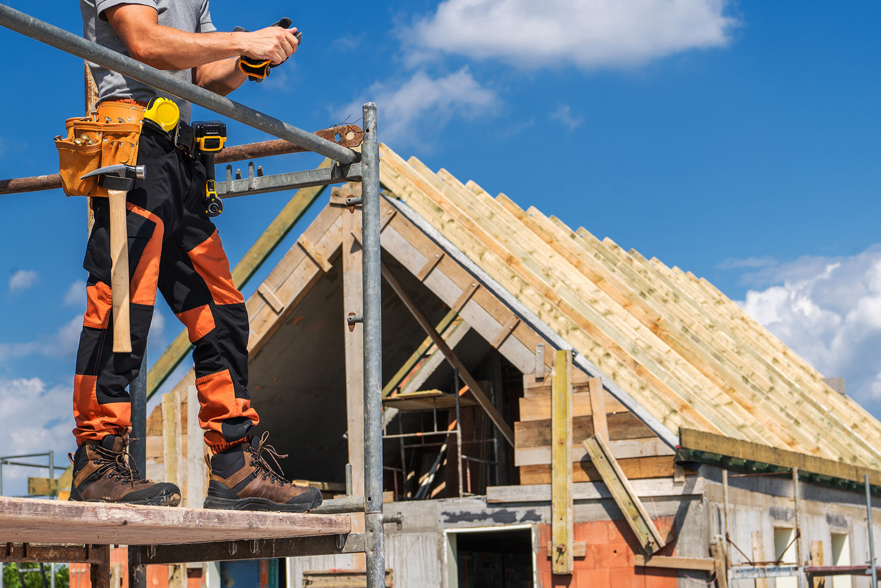Dachdecker GmbH Woldegk Header mobil - Bauarbeiter errichtet den Holzrahmen eines neuen Hauses mit Hammer und Nägeln